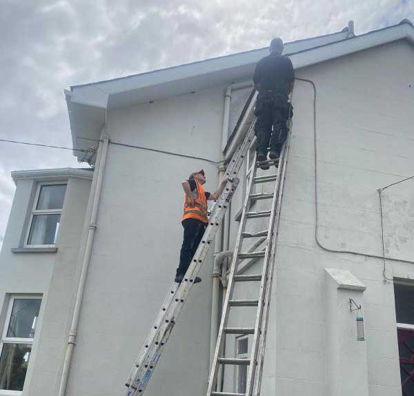 WB Cleaning workmen up ladders fixing guttering